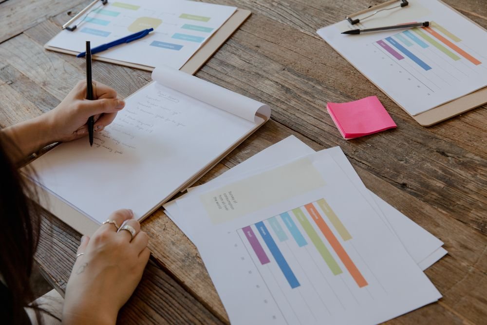 Notoriti CSRD Graphiques Bureau Mains écrivant avec des graphiques colorés sur bureau