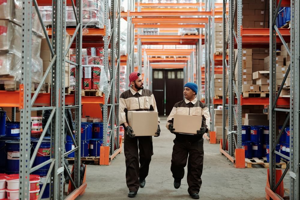 Travailleurs transportant des boîtes dans une allée d'entrepôt