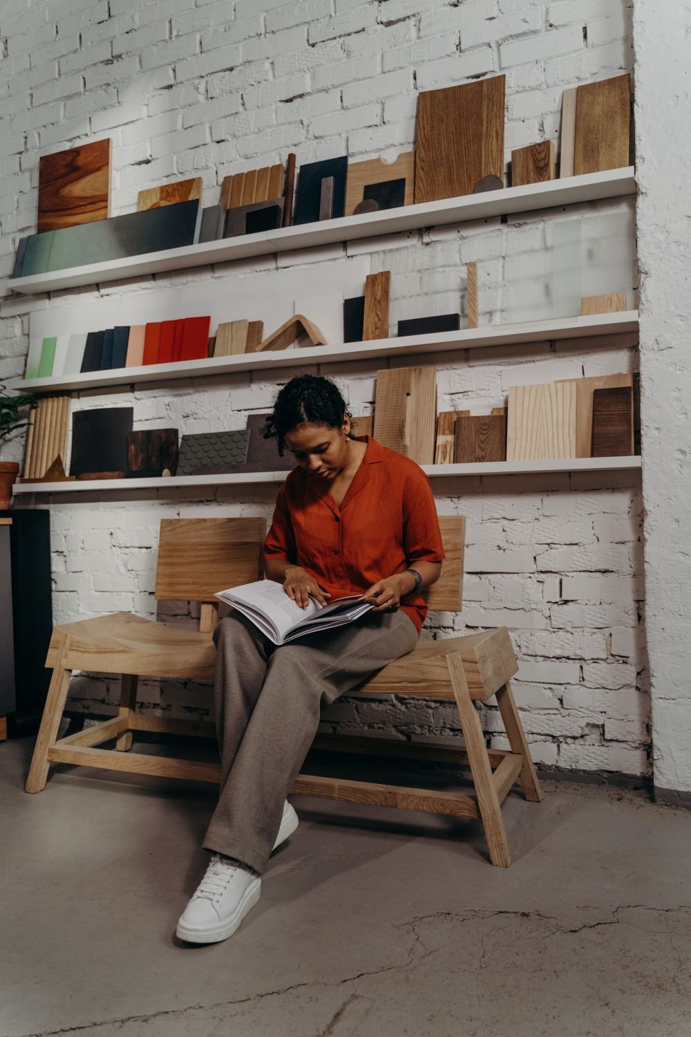 Femme assise sur un banc en bois parcourant un catalogue mobilier